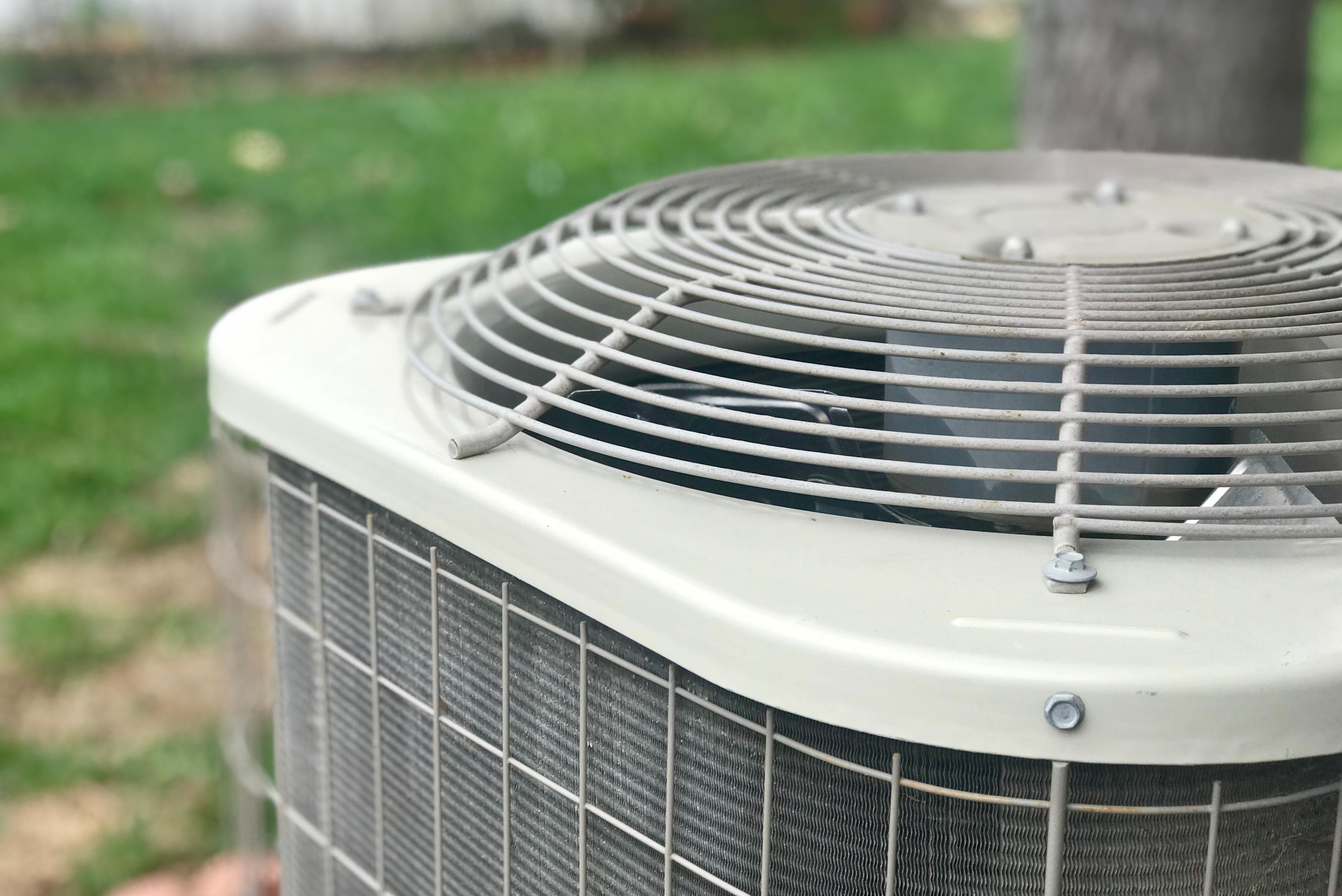 New outdoor AC unit installed in Florida home with green landscaping
